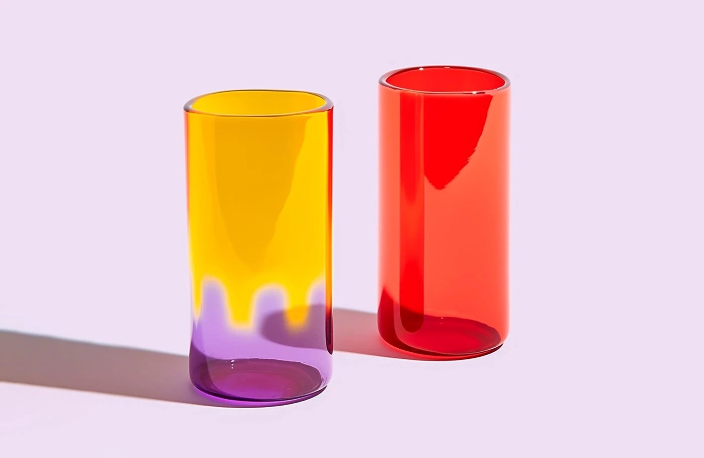 Grandiose Collection glassware brand identity — ruby red and amber short tumblers on lavender background
