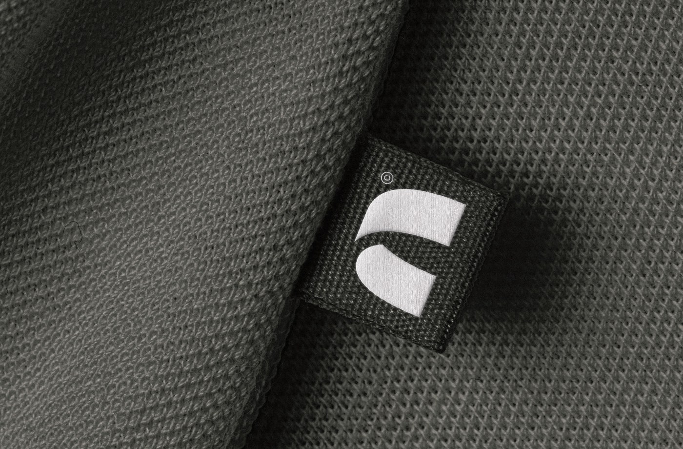 Studio Arch brand identity woven label on olive knit fabric